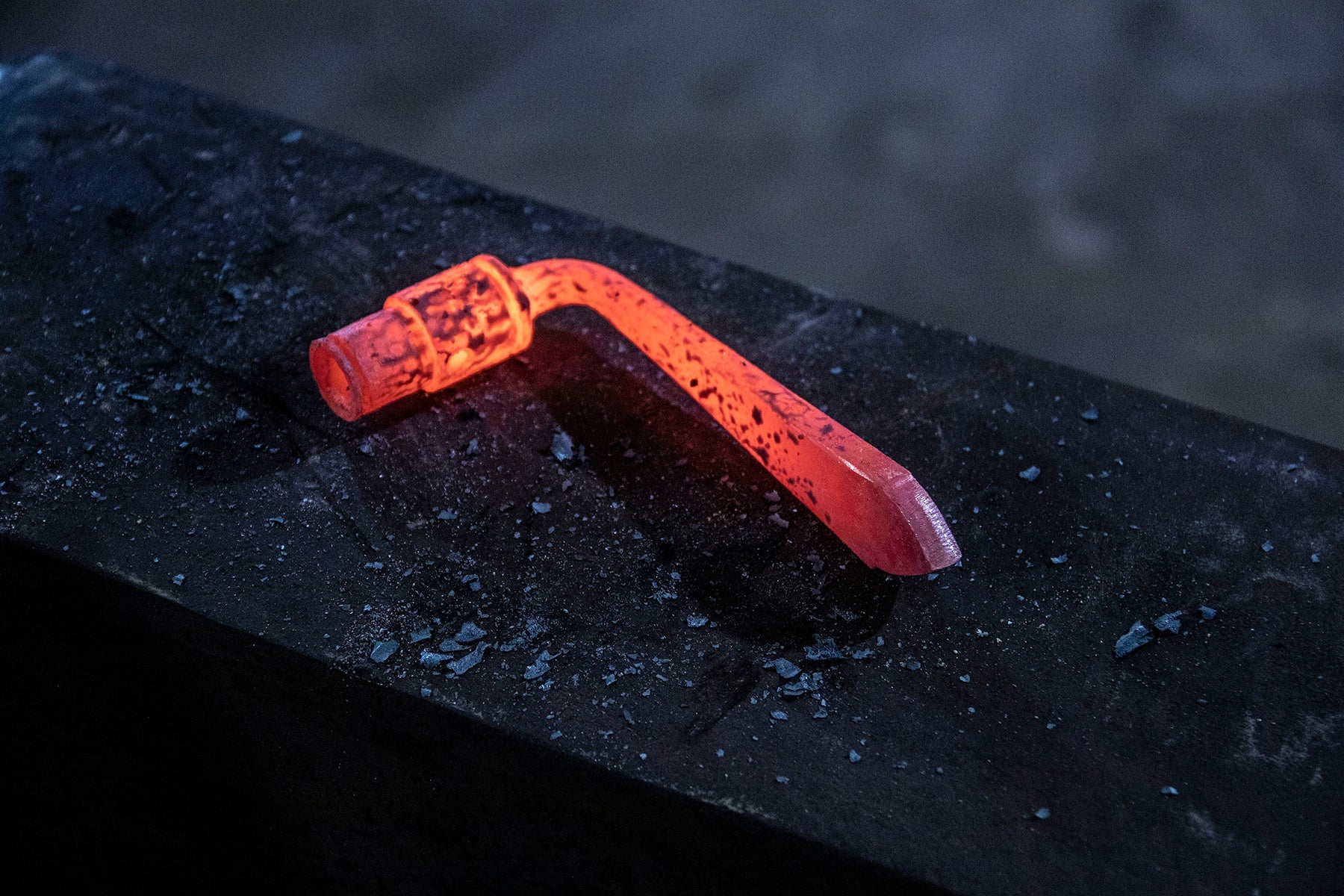 Image of a hot iron nail being hand forged on an anvil