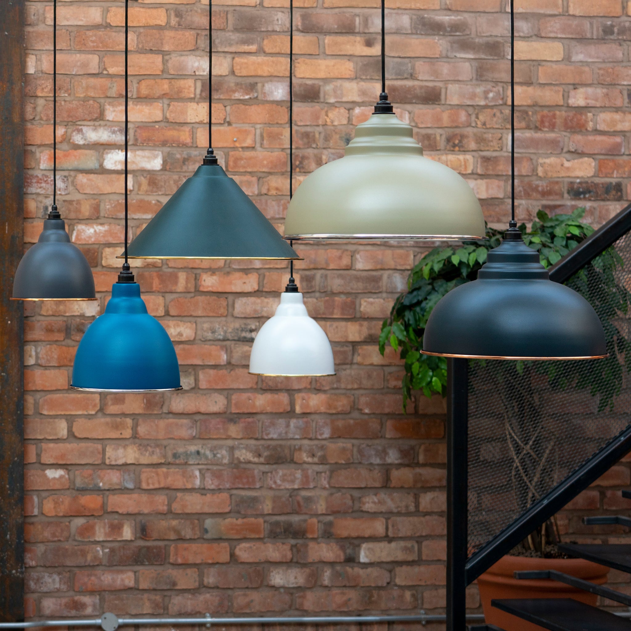 Image of several From The Anvil Lights hanging in front of a brick wall