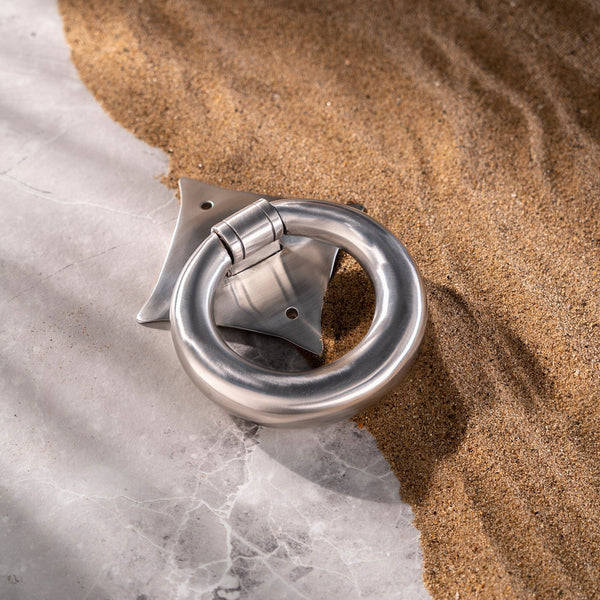 Stainless steel door knocker on sand 