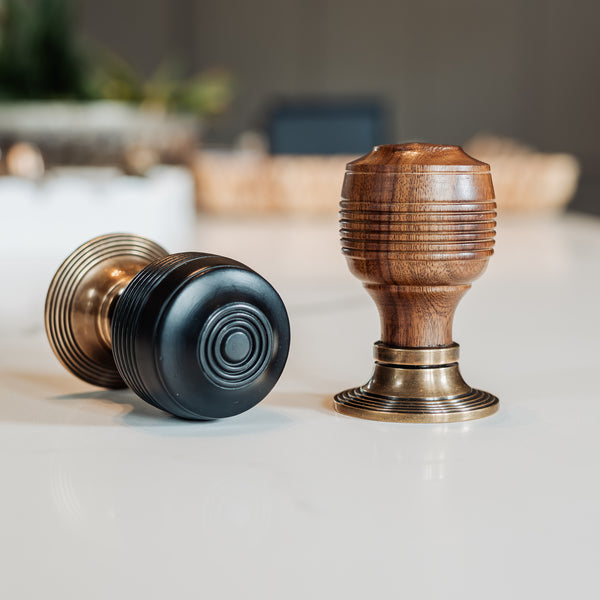  Two door Georgian knobs, one black and one wooden with brass accents, on a light surface.