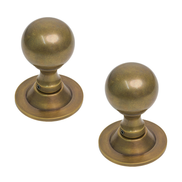  Two round brass door knobs with a polished finish, displayed on a clean white background.