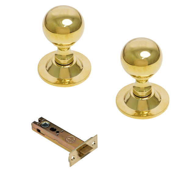 Two round brass door knobs with matching metal strike plates on a plain white background.